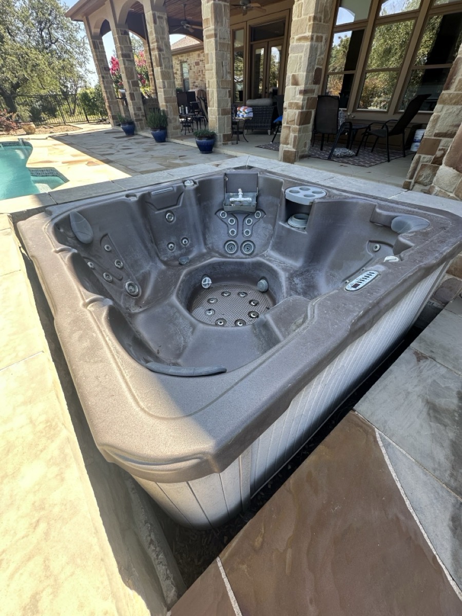 Hot tub sitting on a stone patio before removal in Central Texas